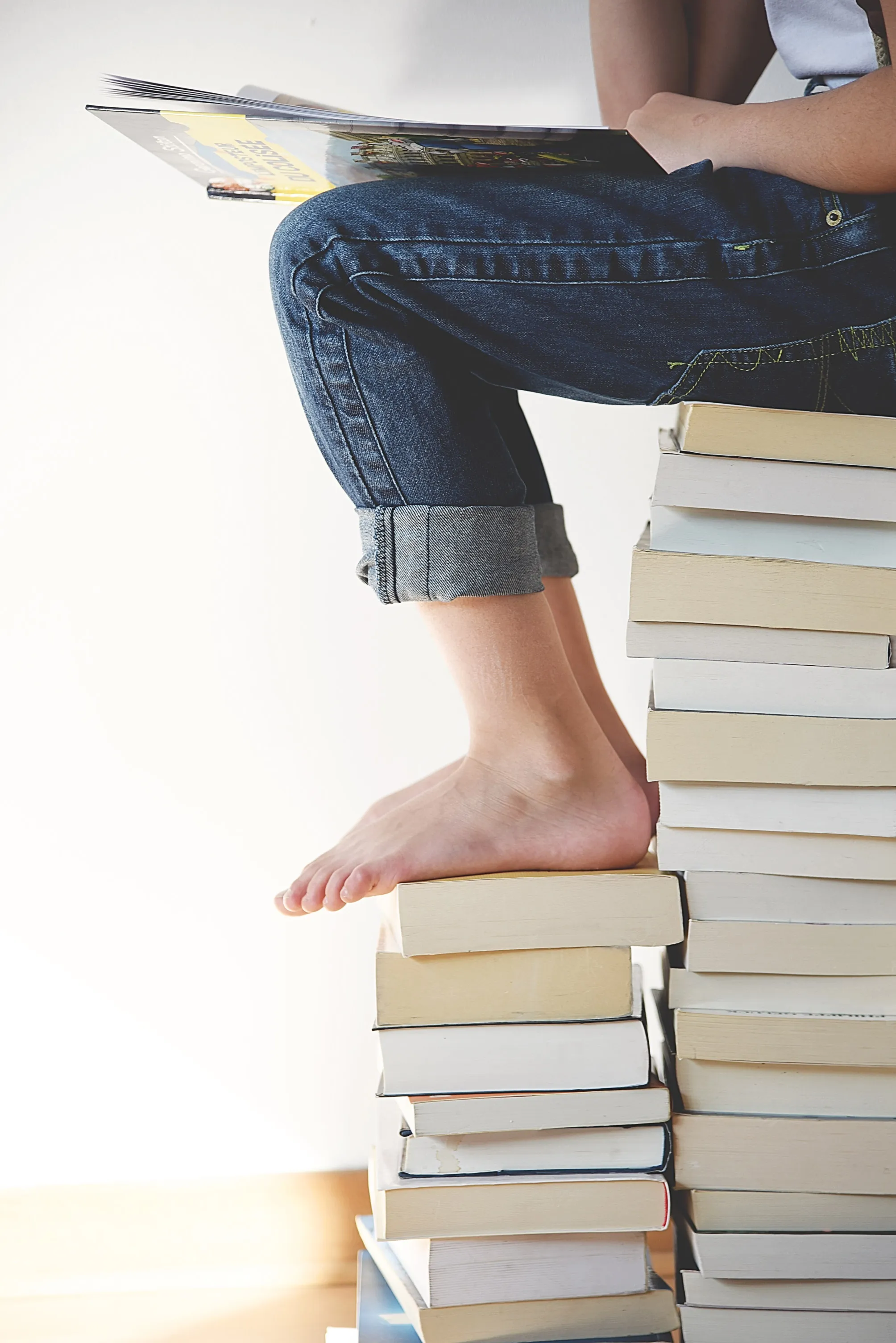 A photo of someone sitting on a stack of books and reading